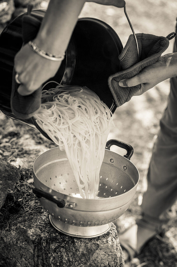 Cooked spaghetti being drained in a colander