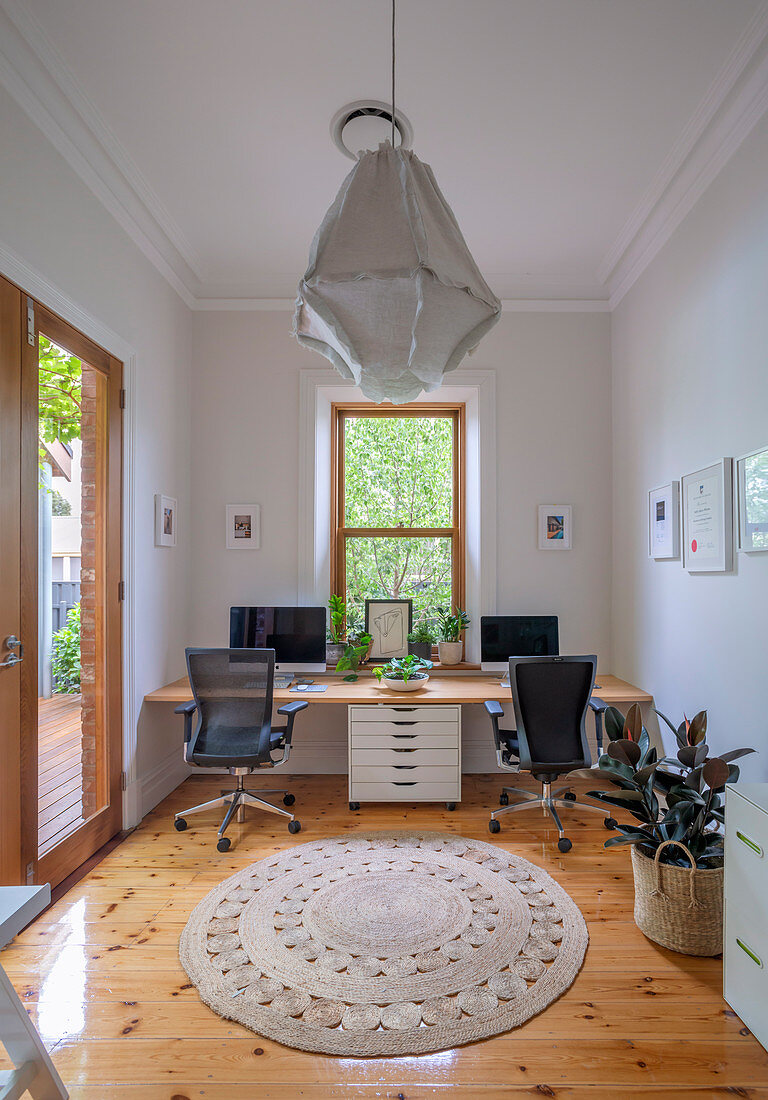 Arbeitszimmer mit Schreibtischplatte und zwei Sitzplätzen vorm Fenster