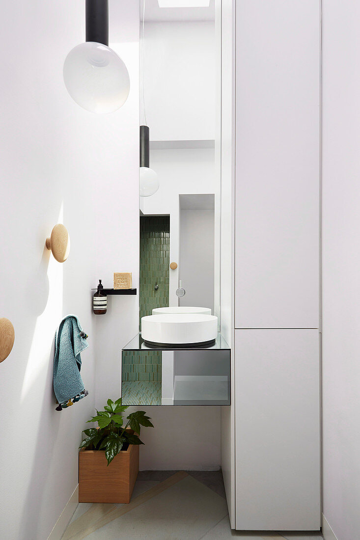 Modern round washbasin on mirrored hanging table in bathroom niche