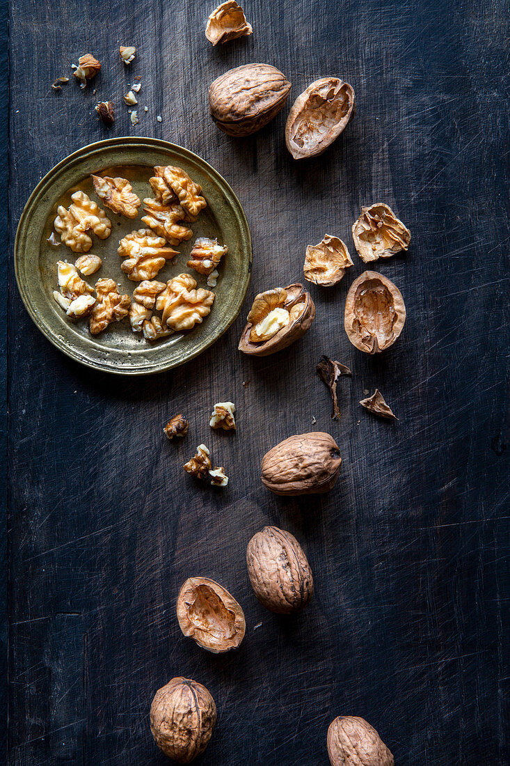 Walnuts and nutshells over black wooden background