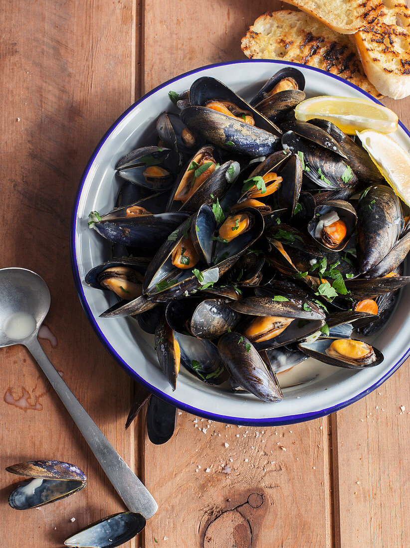 Bowl of Mussels in white wine and garlic on wooden background