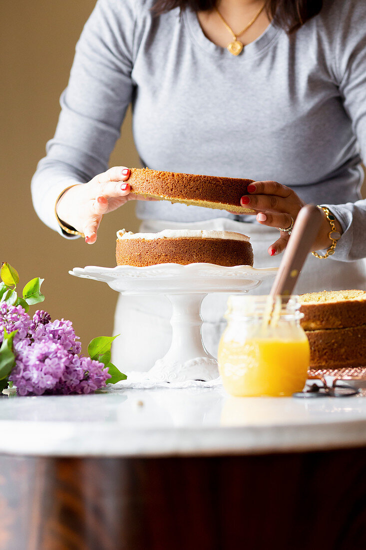 Frau beim Zusammensetzen der Böden einer mehrschichtigen Torte