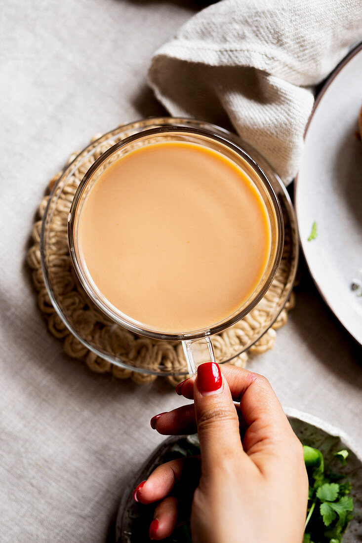 Frauenhand hält Tasse mit Chai-Tee