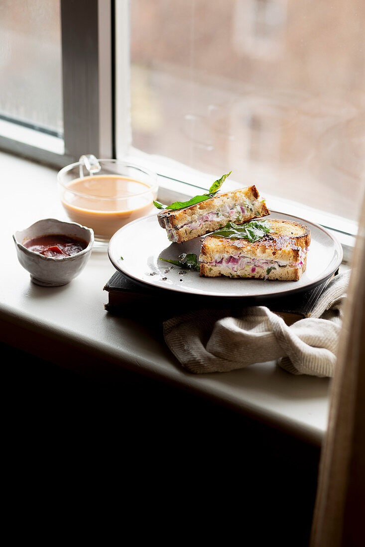 Indisches Joghurt-Sandwich serviert mit Chai-Tee auf Fensterbank