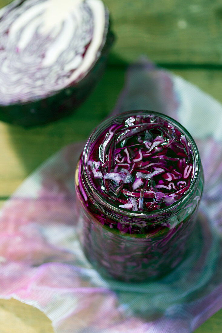 Glass jar full of tasty fermented red cabbage placed on wooden table