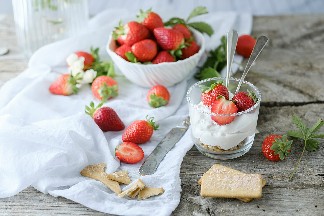 Sahnecreme mit Erdbeeren im Glas auf rustikalem Holztisch