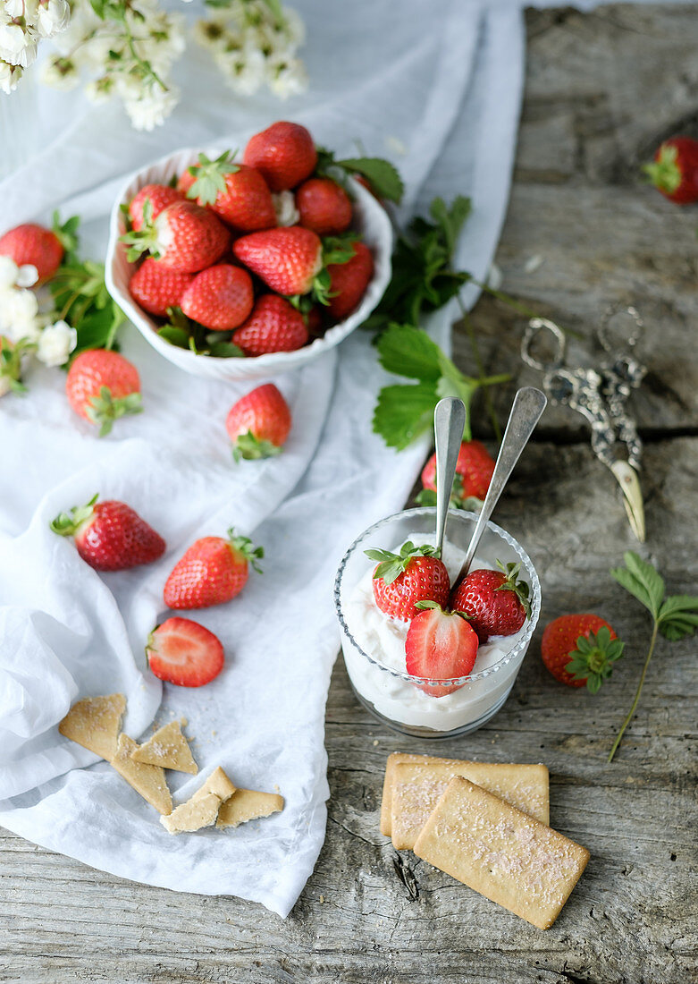 Top view of creamy sweet dessert with fresh juicy tasty strawberries served inside a glass on a rustic wooden table