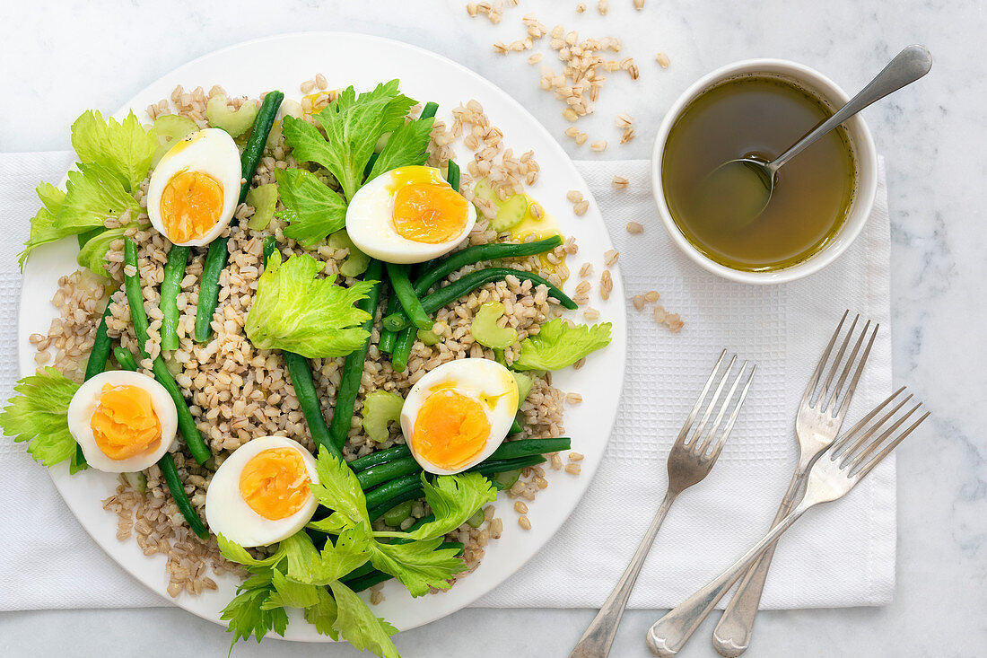 Bean, barley and egg salad with forks and a bowl of dressing