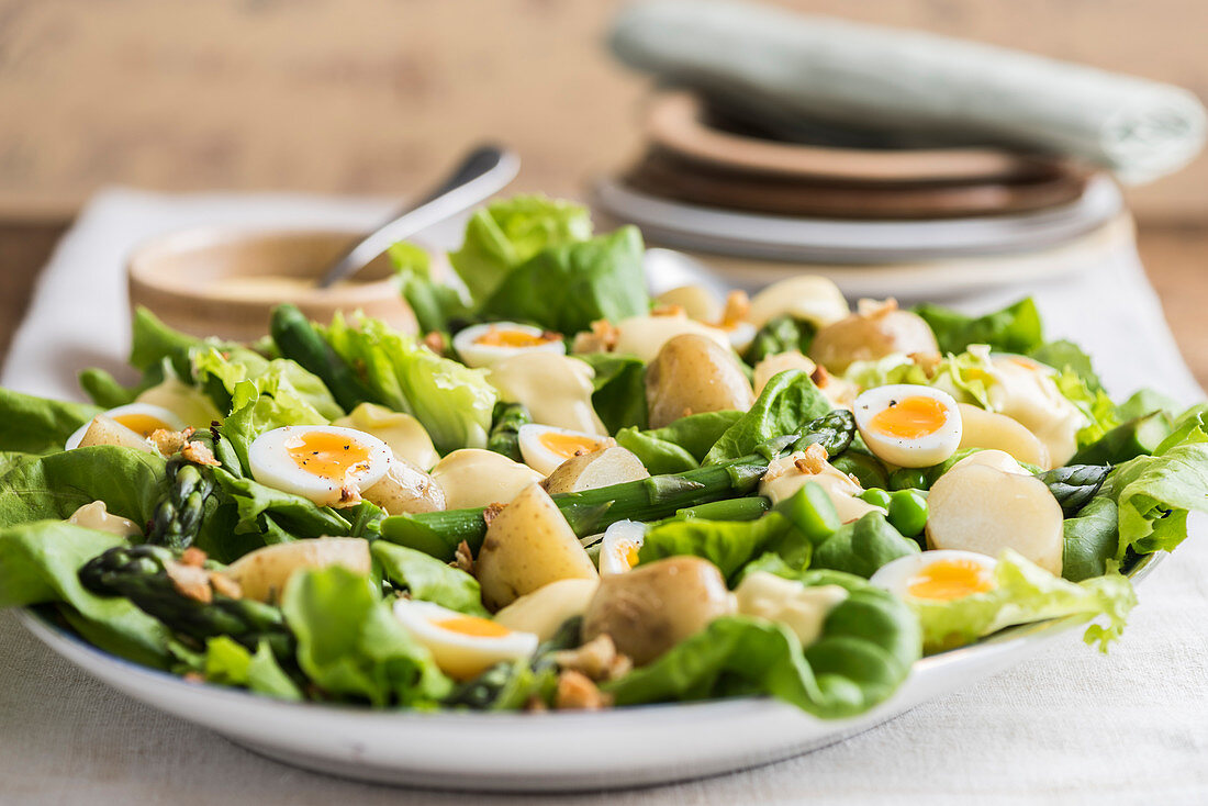 Kartoffelsalat mit Blattsalat, grünem Spargel, Erbsen und Wachteleiern