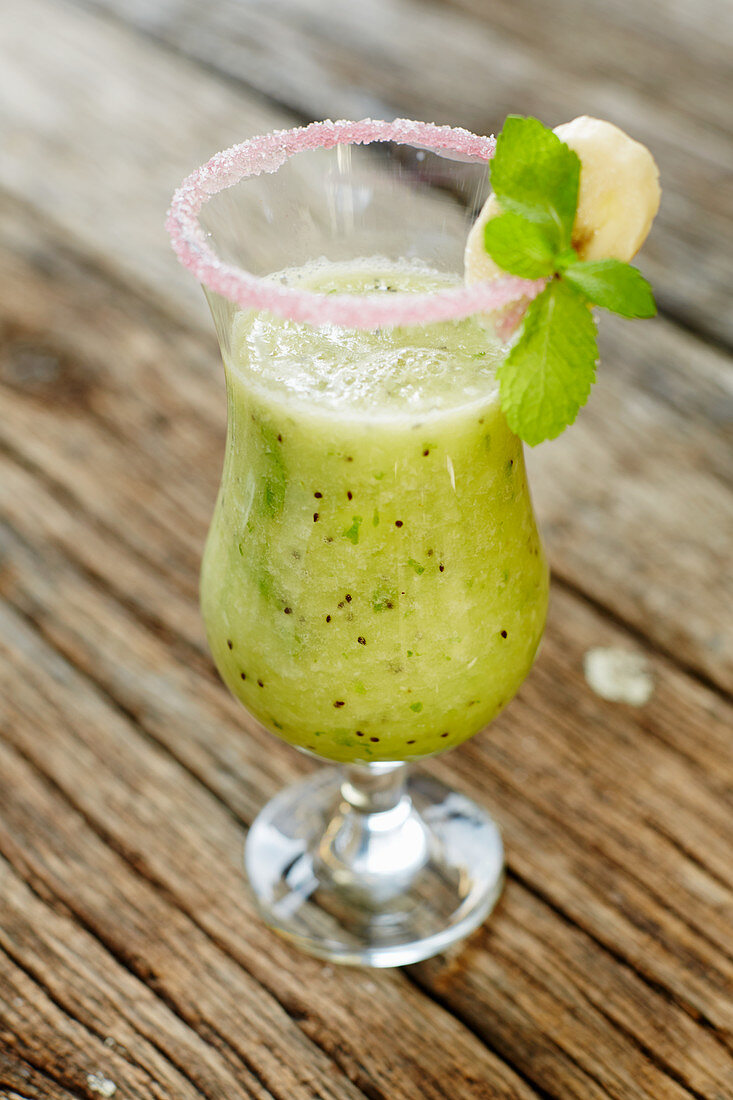 A kiwi smoothie in a glass with a sugared rim