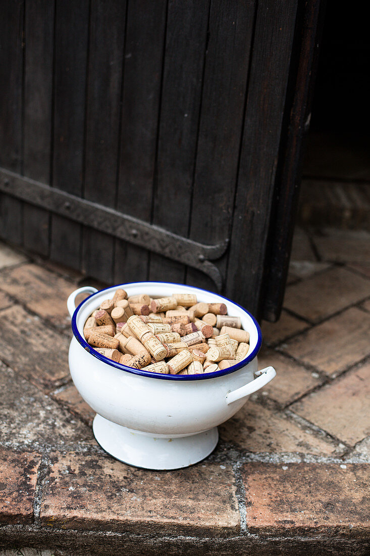 Wine corks in n enamel bowl in front of a wooden door