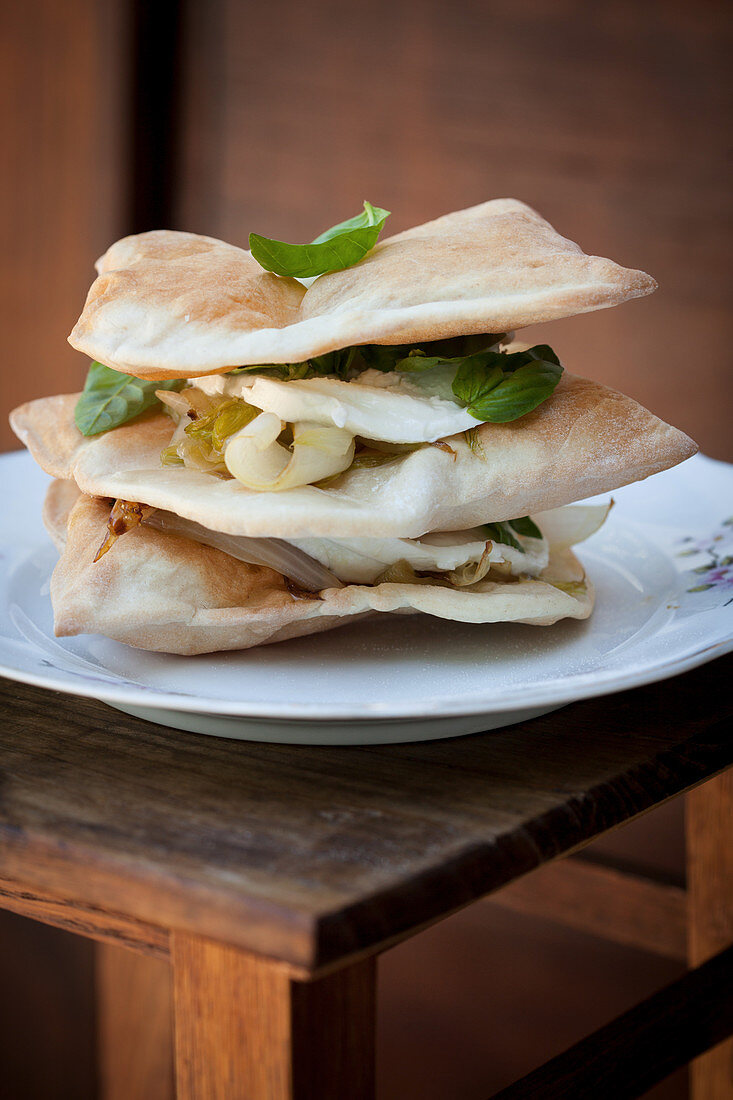 Gestapelte Blätterteigkissen mit Zwiebeln und Mozzarella