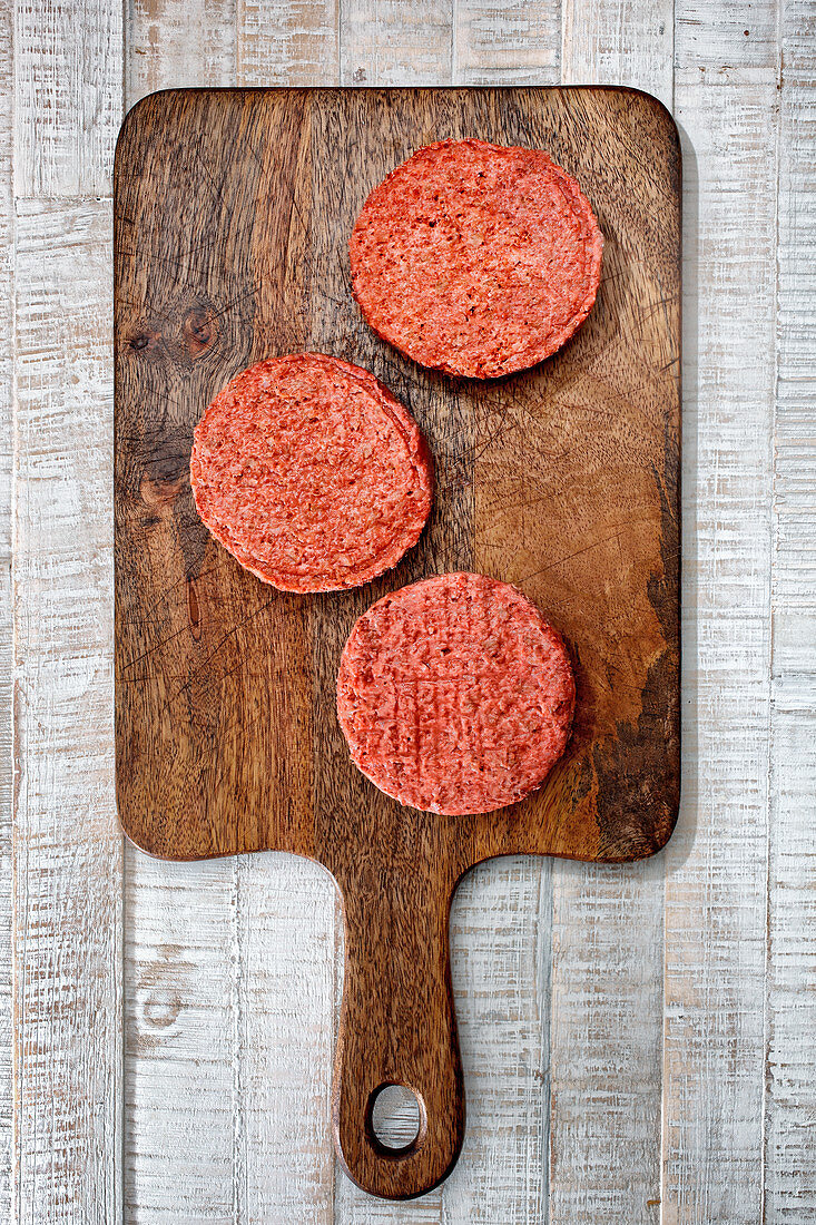 Rohe Hamburger Patties auf Holzschneidebrett