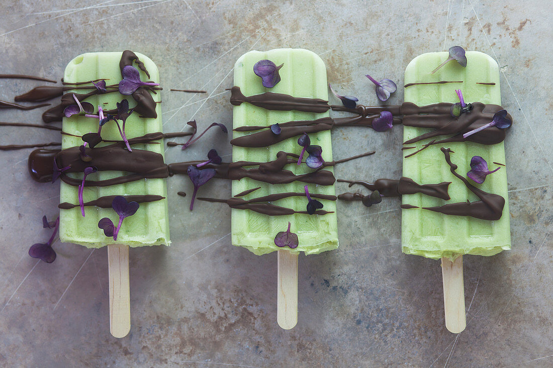 Avocado and lime ice cream on a stick with chocolate and radish cress