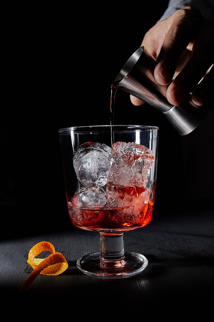 Vermouth poured from a measuring glass into a Negroni cocktail