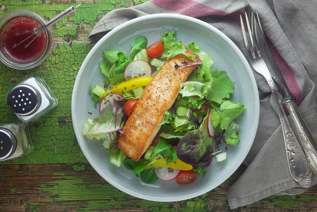 Salad leaves with salmon fillet, cherry tomatoes and radishes