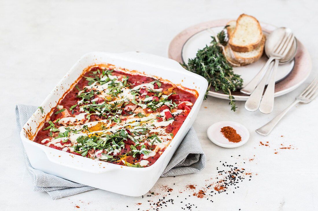 Shakshuka in a baking dish with parsley, turmeric and tahini sauce