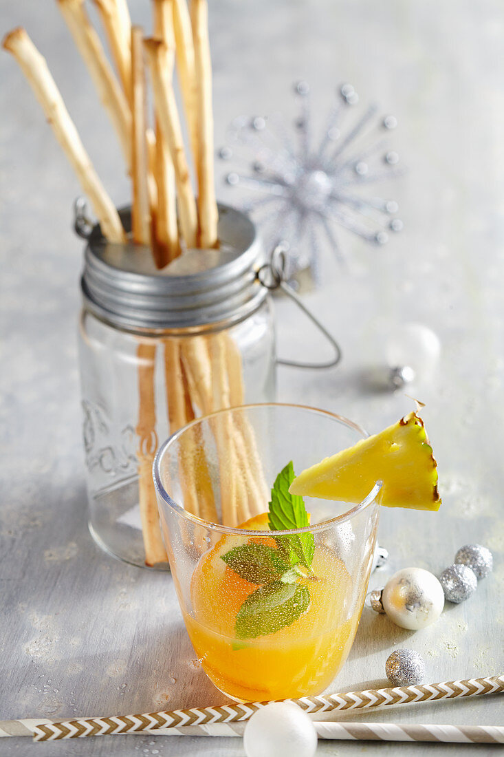 Weihnachtlicher Cocktail aus Winterapfel-Likör, Apfel- und Orangensaft mit Ananas