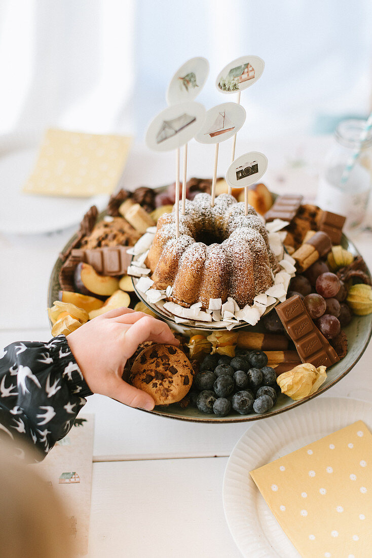 Sweets, fruits and cake on cake stand with decorative skewers