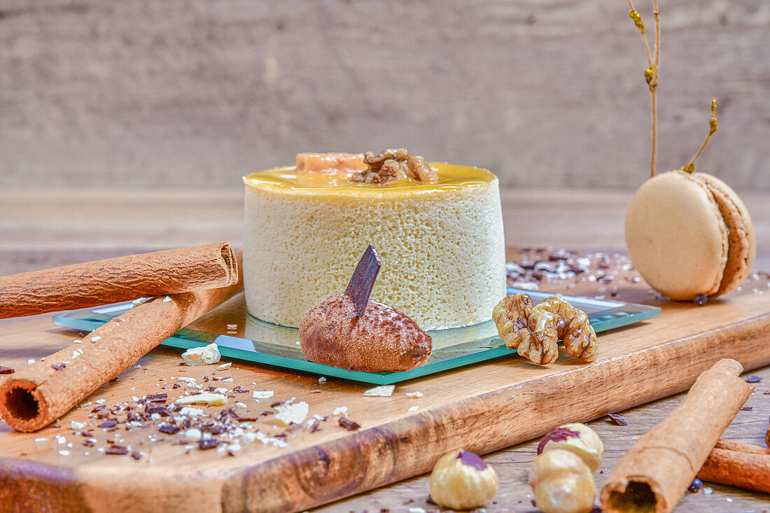 Arranged sophisticated Timbale de Bavarois dessert on board among spices and nuts on table