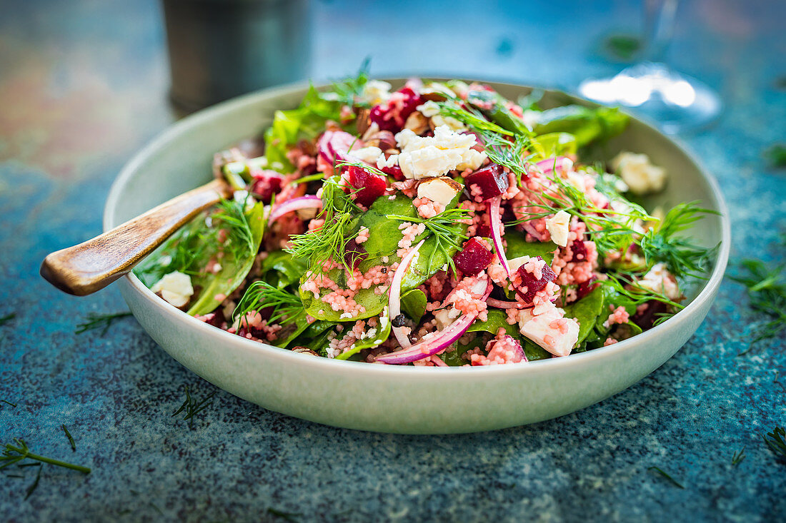 Bunter Couscoussalat mit rote Bete, Spinat und Feta, bestreut mit Haselnüssen und Dill