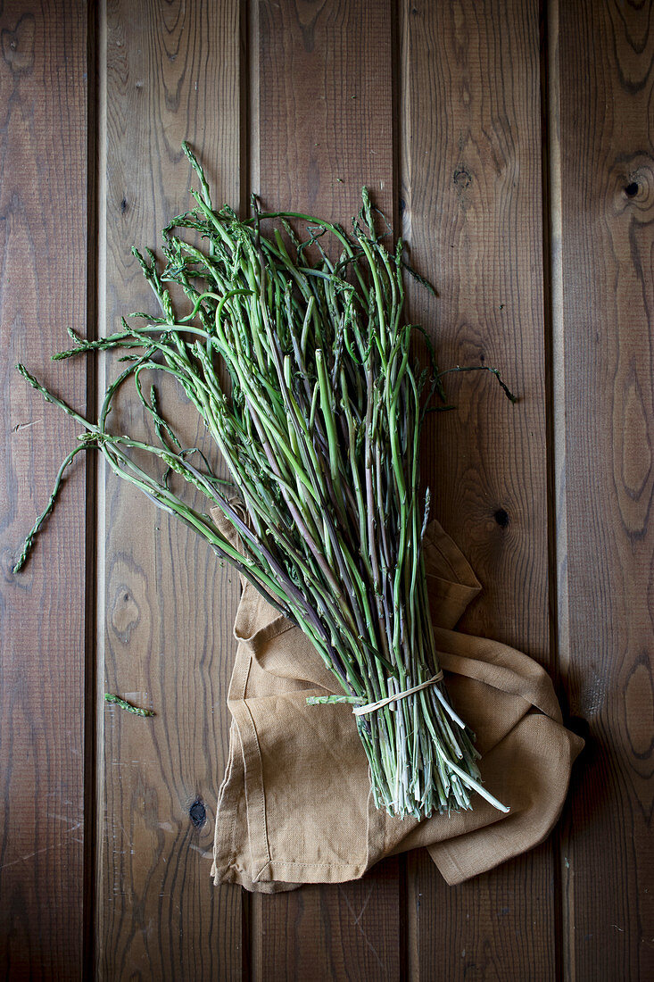 From above of bundle of green asparagus on wooden table