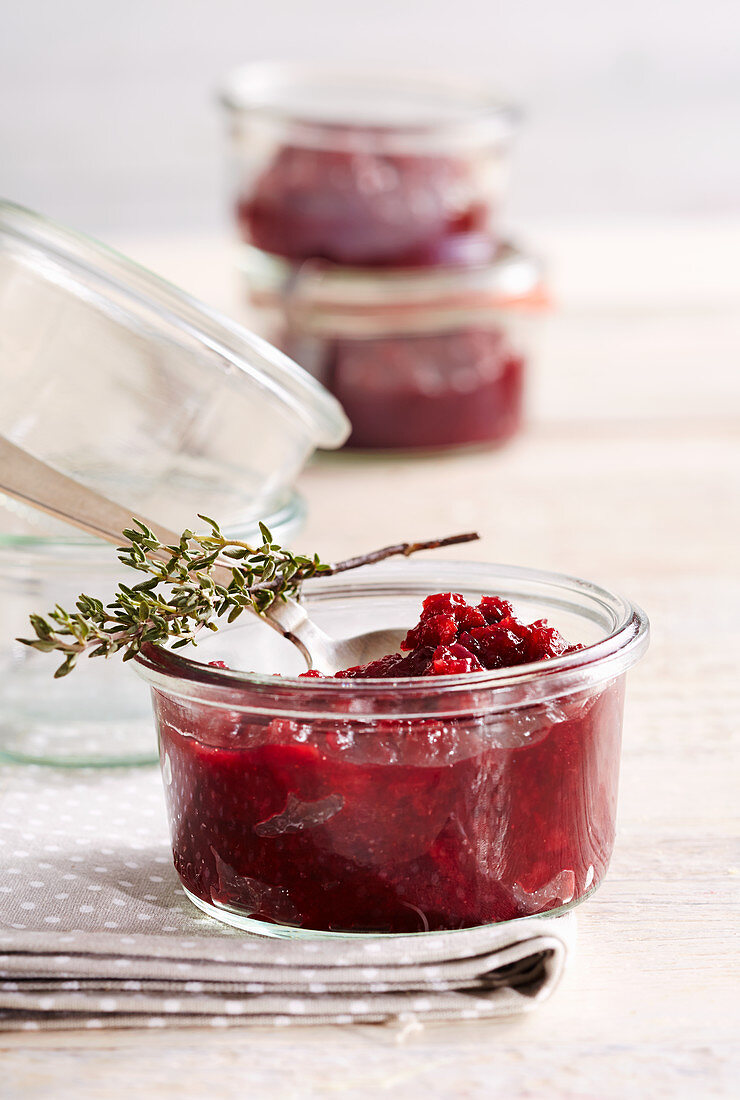 Spicy sour cherry chutney in a preserving jar with thyme