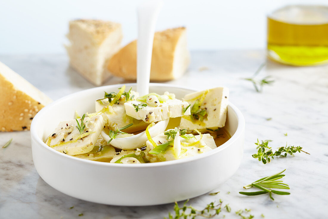 Pickled feta cheese in olive oil with garlic, spring onions, thyme, rosemary and lemon pepper