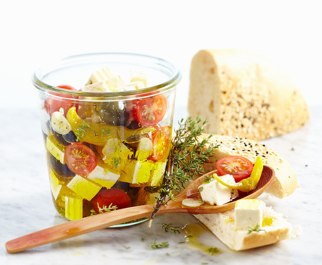 Feta cheese preserved in olive oil with tomatoes, garlic, jalapenos and olives served with unleavened sesame seed bread
