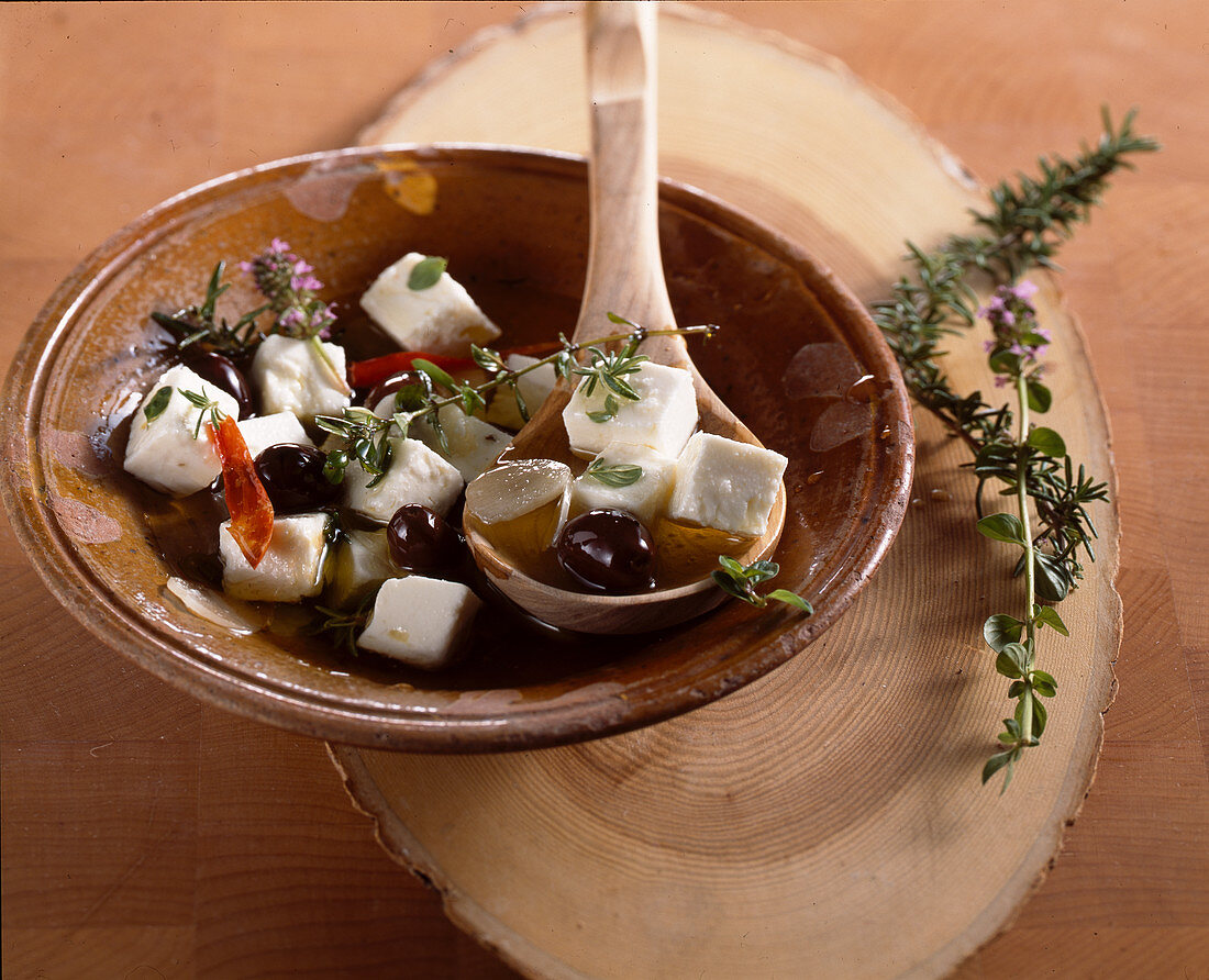 In Olivenöl eingelegter griechischer Schafskäse mit Knoblauch, Thymian, Rosmarin, Kräuter, Chili und Oliven