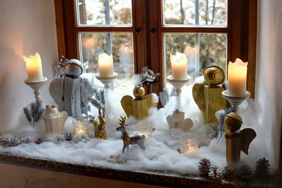 DIY-Weihnachtsengel und Kerzen umgeben von Schneewatte auf Fensterbank