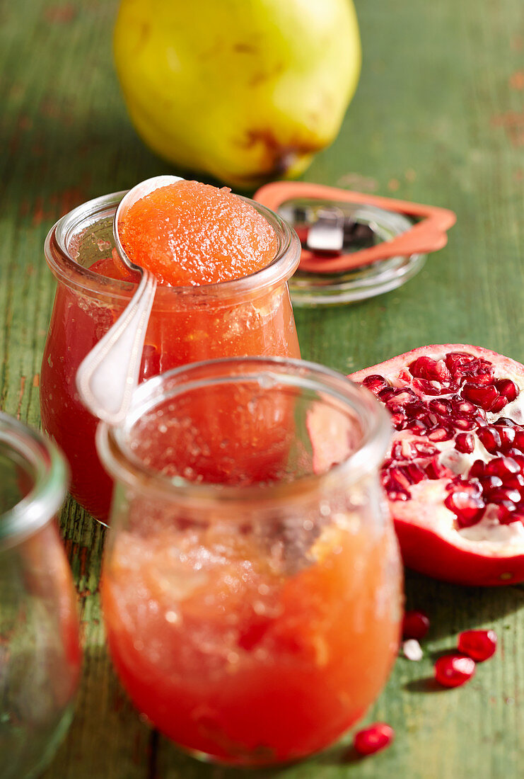 Jars of quince and pomegranate jam with a silver spoon