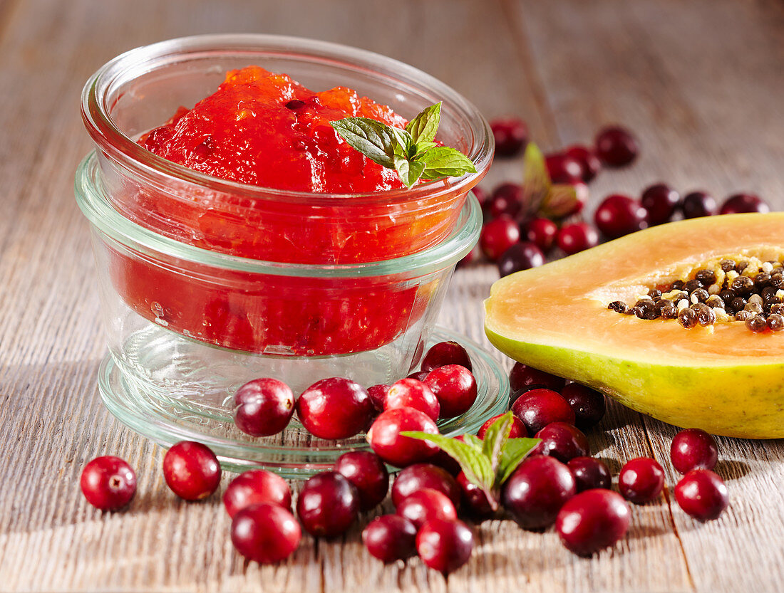 Papaya and cranberry jam in a jar on a wooden surface