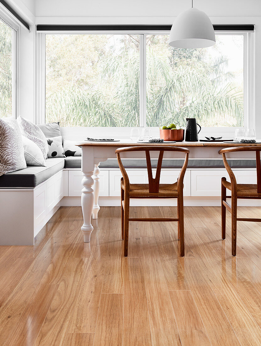 Designer chairs at farmhouse table with corner bench