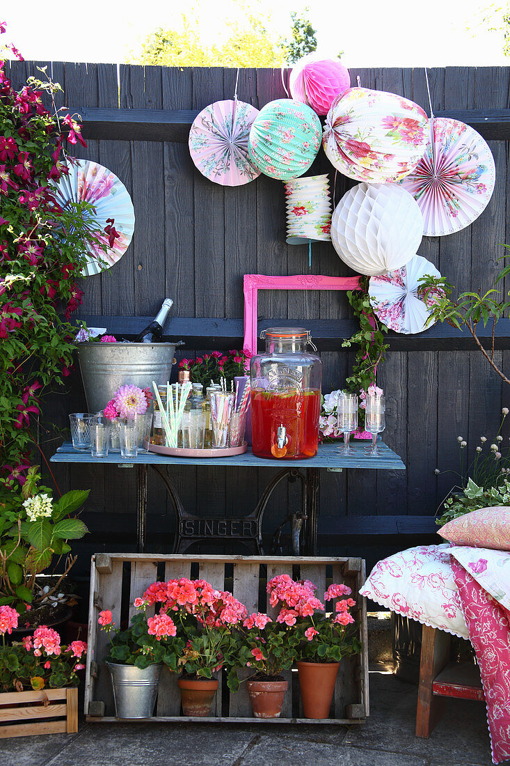 Small drinks table with lanterns and geraniums in garden