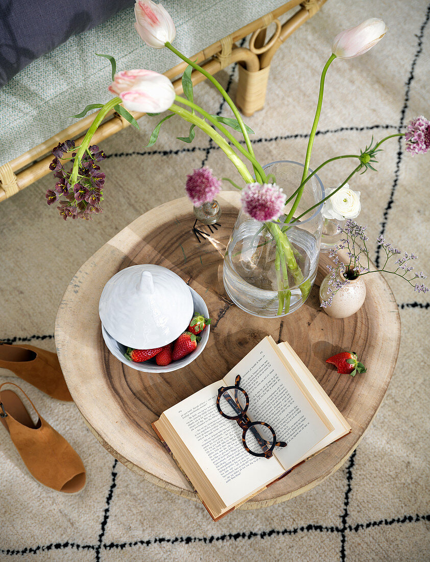 Open book, strawberries and flowers on coffee table