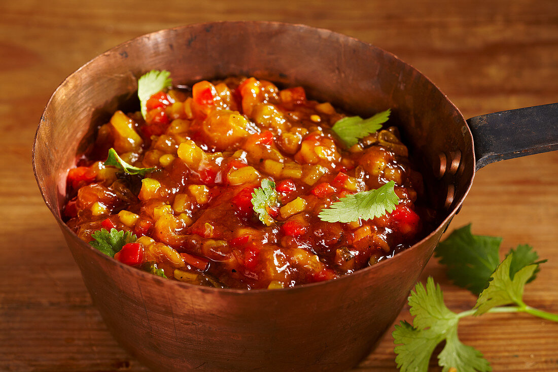 Fruit and vegetable relish with nectarines, pepper and spices in an antique copper pot
