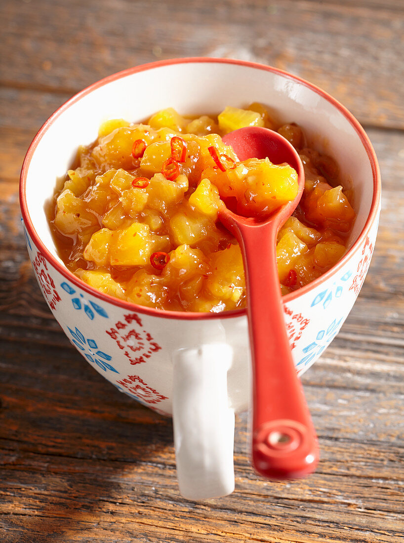 Spicy papaya and pineapple chutney with ginger, chilli and vinegar in a ceramic cup