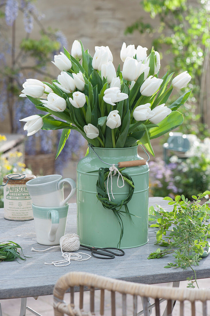 White bouquet of tulips in tin can, wreath of grass as decoration