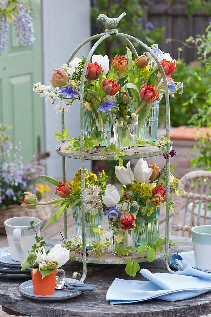 Cake stand with bouquets of tulips, lilac, columbine, roses and milkweed