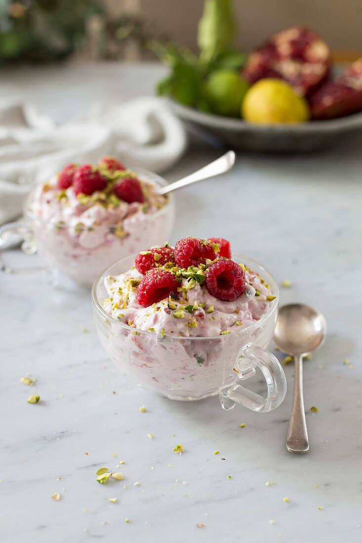 Eton Mess with raspberries and pistachio nuts served in glass cups