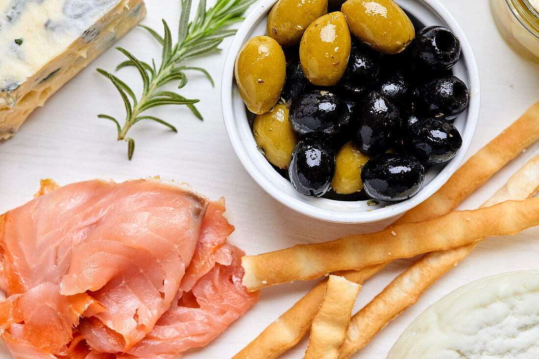 A Mediterranean appetizer platter with cheese, salmon, olives and bread sticks