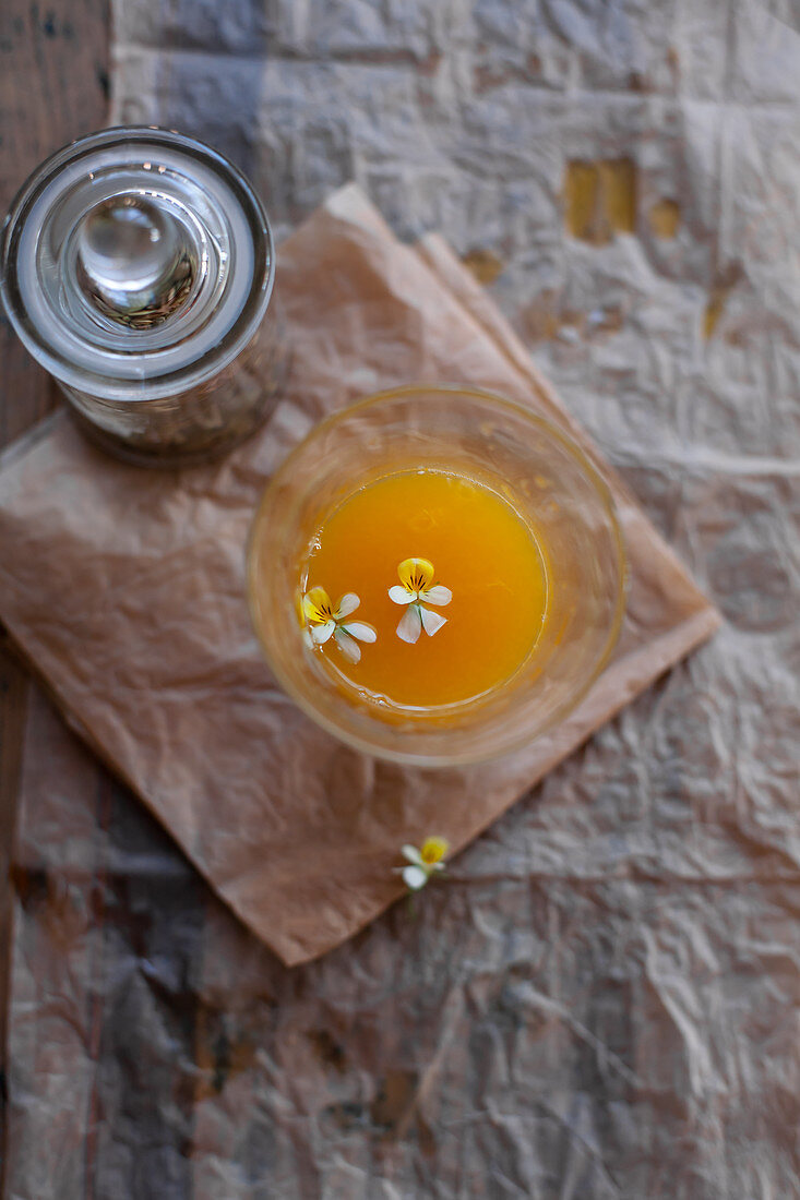 A glass of orange juice with flowers