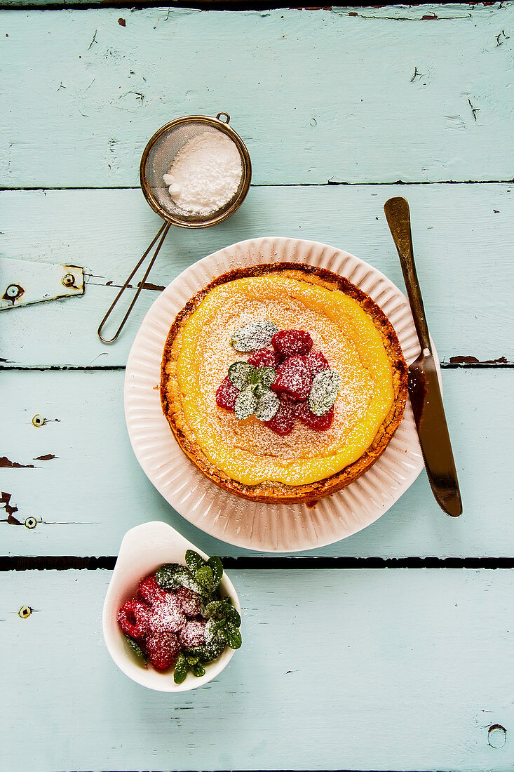 Classic cheesecake with raspberry and icing sugar on turqouise background