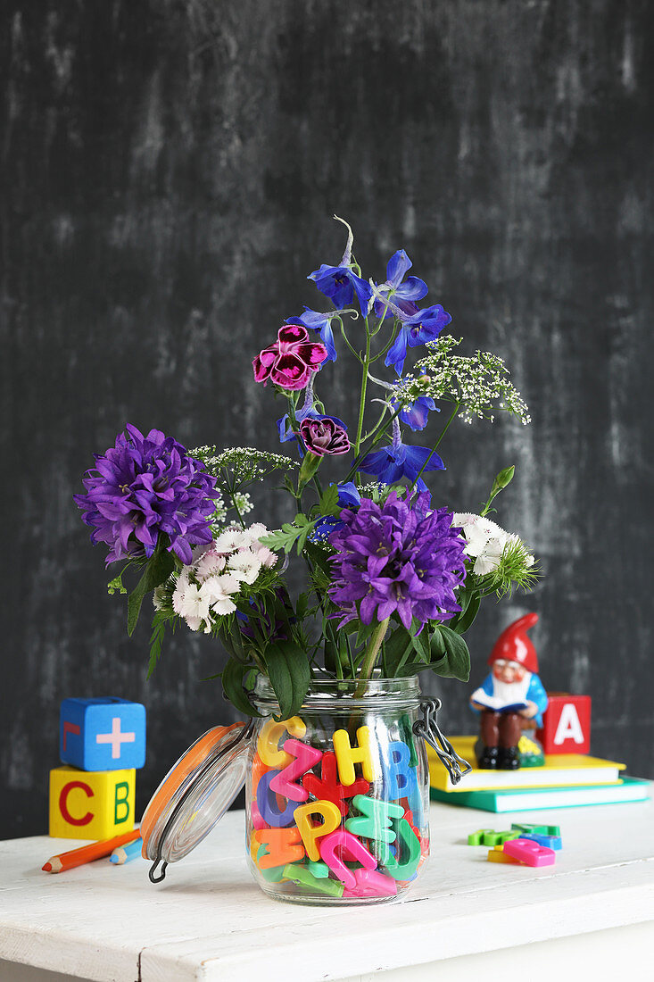 Flowers in preserving jar of water and colourful letters