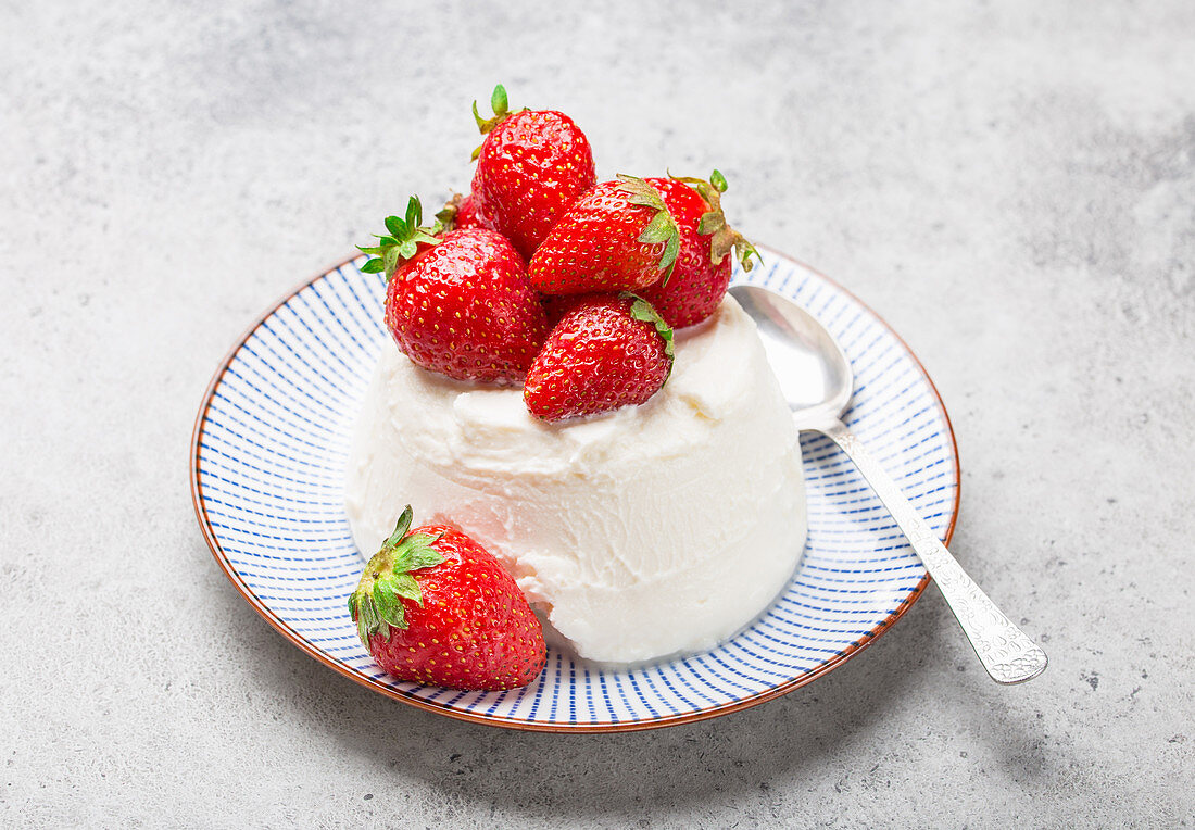 Fresh Italian cheese ricotta with strawberries on a plate with a spoon