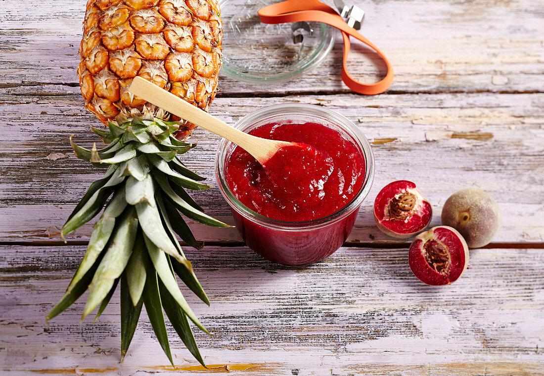 A jar of pineapple jam with red vineyard peaches