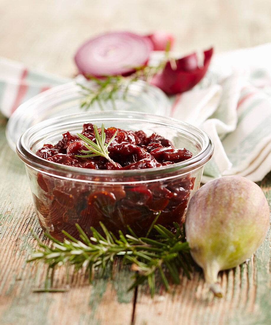 Homemade fig and cherry chutney with rosemary in a glass jar