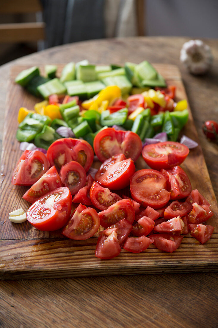 Chopped gazpacho vegetables on a wooden board