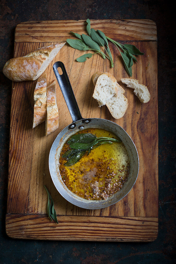 Salbeibutter in Pfännchen und Weißbrotscheiben